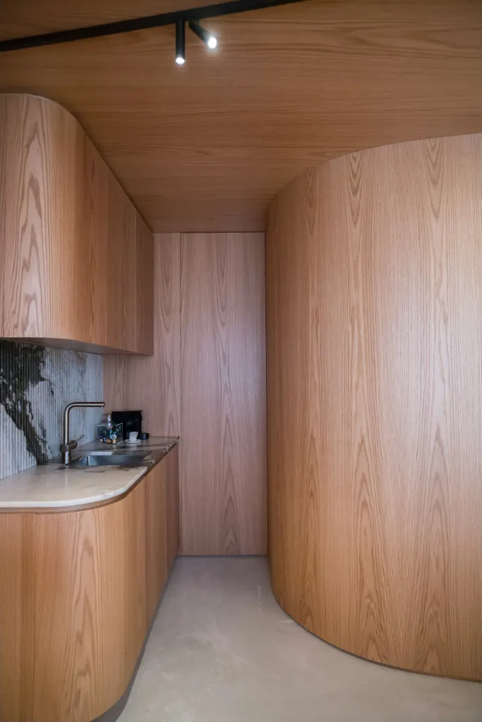 The kitchen of Arc Apartment, wrapped in a curved oak wall