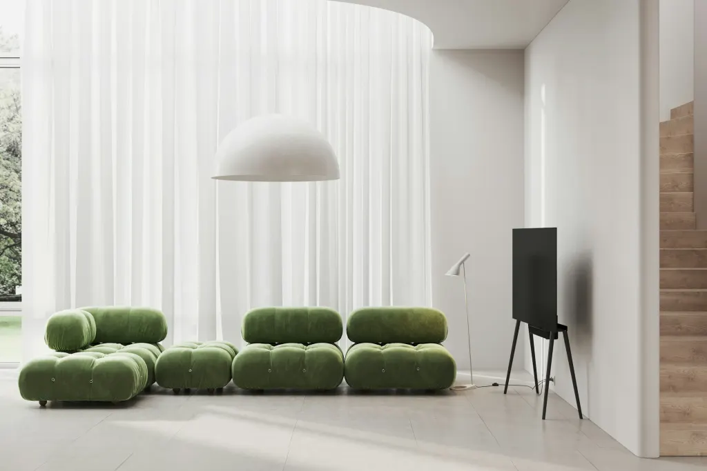 A green sofa and a white lamp by the window