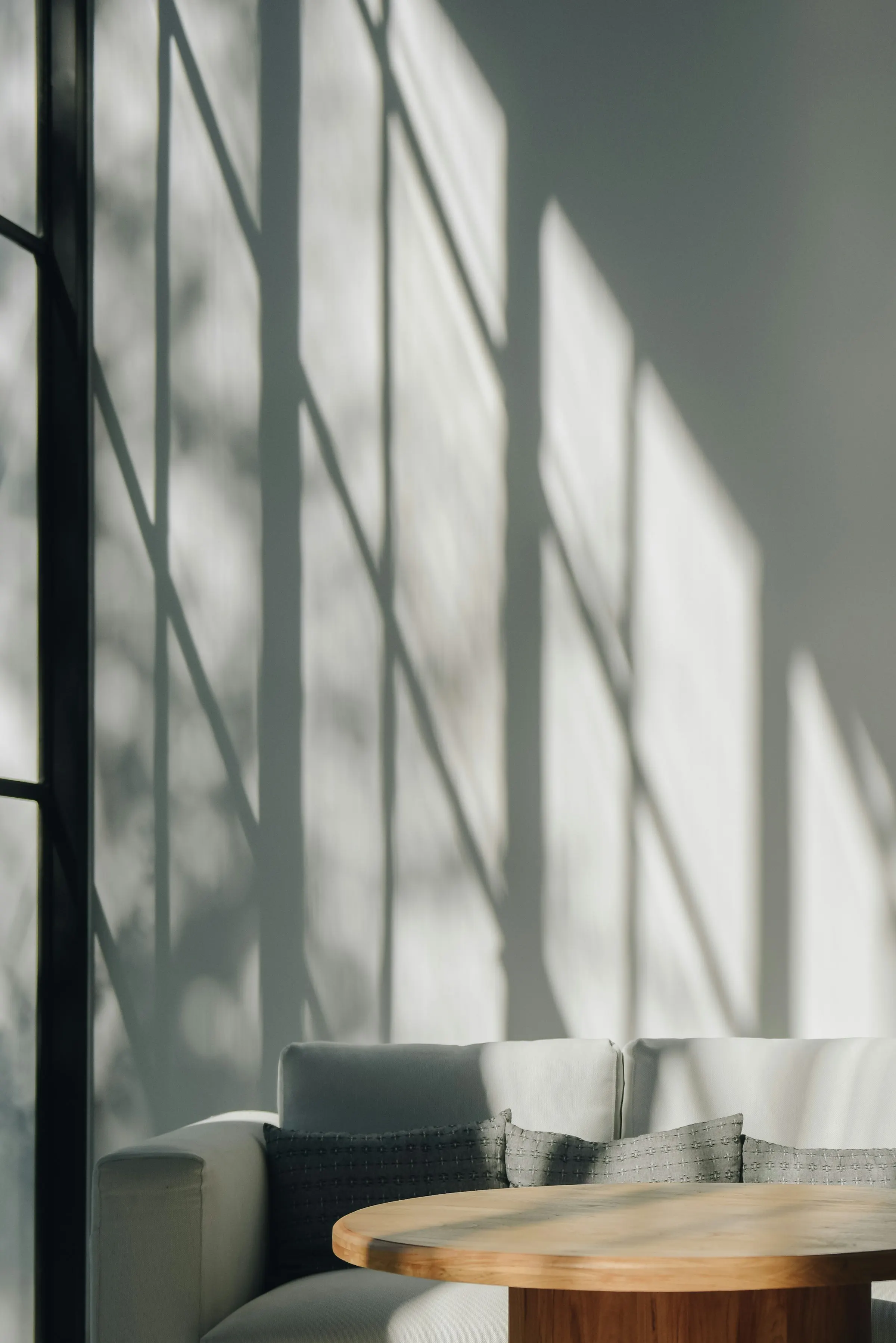 Morning light drawing shadows on the living room wall of Lumina House