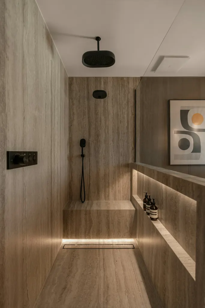A lit niche in a travertine bathroom