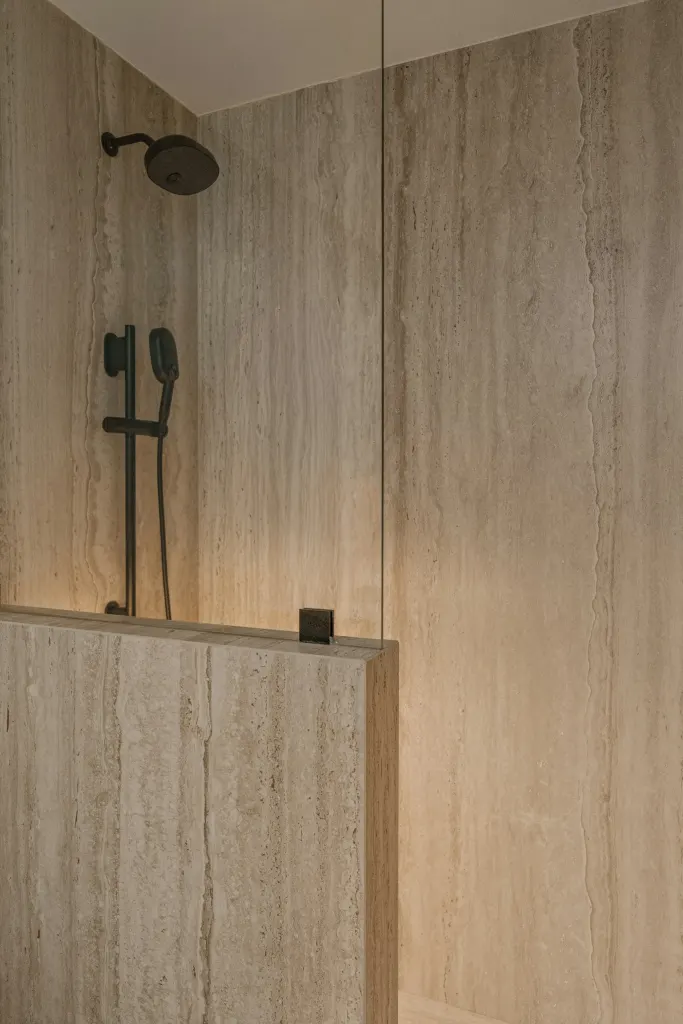 A shower in travertine tiles with black fittings