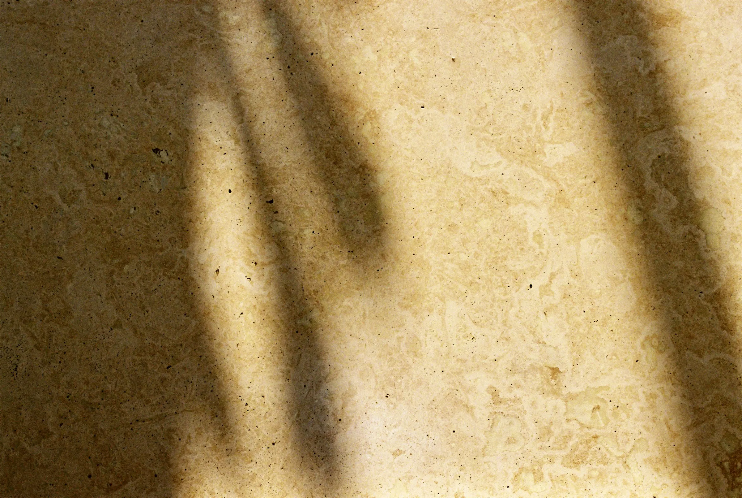 A cream stone floor with soft window shadows