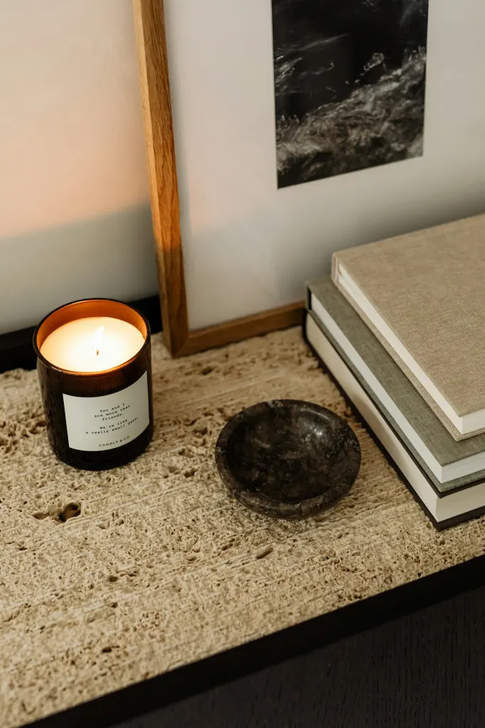 A lit candle and a small dish on a textured stone counter