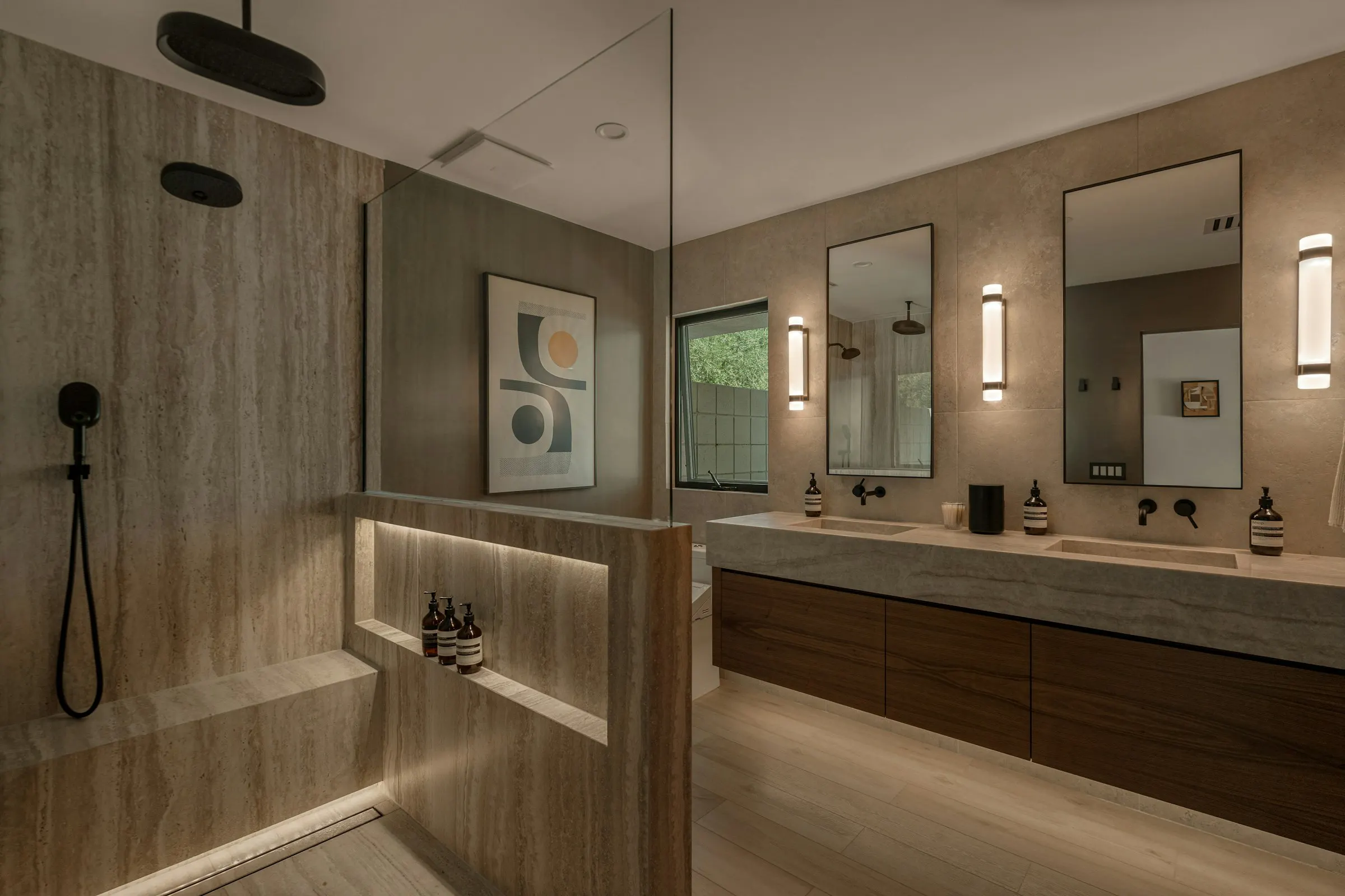 The main bathroom of Travertine House: travertine walls, hidden lighting and dark wood furniture